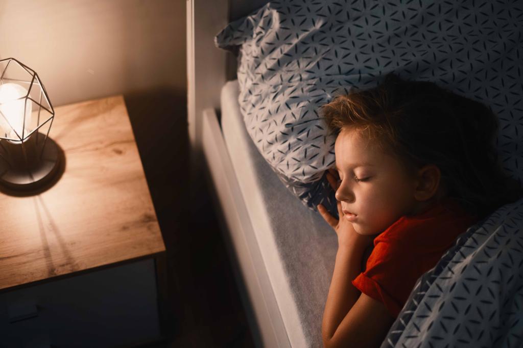 A young child sleeping in bed with their head on a pillow.